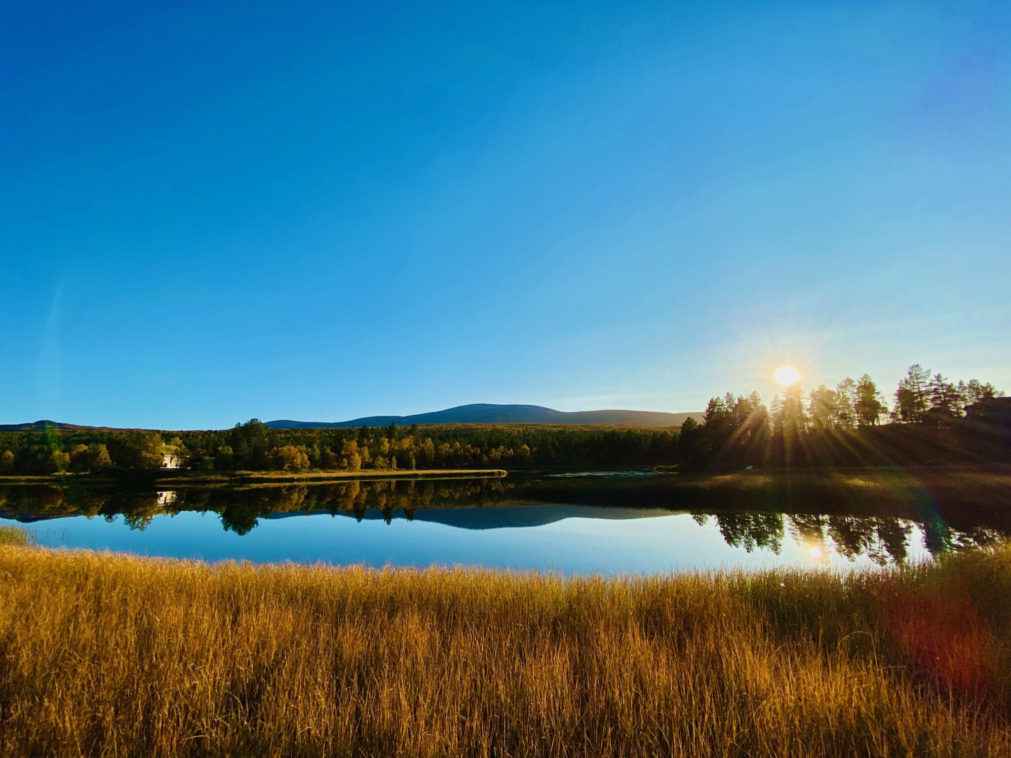 Klar, blå himmel med høstsol over stille vann